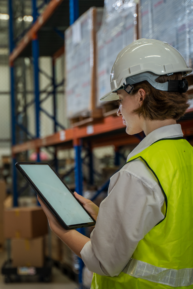 Alumna de FPLogis en un almacen logistico ordenando cajas y pedidos con un dispositivo tecnologico