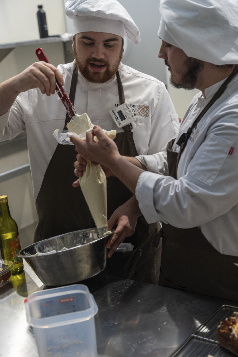 Dos alumnos aprenden de forma práctica en las enormes instalaciones de Campus Córdoba y la Escuela superior de hostelería de españa. Preparan una receta de un dulce típica de andalucía.